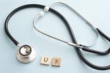 User experience health care concept with letters and medical stethoscope over gray background