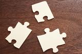 Close up of three blank jigsaw puzzle pieces placed in a triangle shape on a wood table