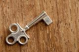 Ornate small cabinet key with three circle cutouts in the handle lying on a wooden surface with copy space