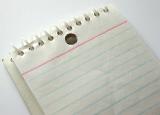 Blank spiral bound notepad with ruled lines on a white background, close up view of a portion of the pad