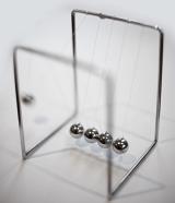 Newtons cradle executive desk toy with five suspended metal balls which transmit motion when one end ball is raised and released