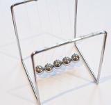 Newton's cradle executive toy with five suspended metal balls to show the conservation of energy and motion