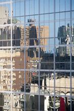 Reflections of highrise urban buildings in a modern glass-walled office block