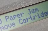 Close up view of a printer warning for a paper jam. The message tells how to remove the paper jam.