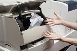 Frustrated person with ink on their hands trying to clear a paper jamb in an office printer