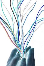 Artistic abstract with multicoloured electrical wires beign streamlined by cupped hands