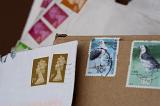 Background of a variety of cancelled UK postage stamps on white and brown envelopes.