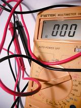 Close Up of Multimeter Electronic Measuring Instrument with Reading of Zero, Black and Red Test Lead Wires on White Background