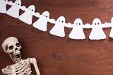 a halloween background featuring a skeleton and a string of ghosts