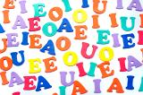 Colourful randomly scattered plastic vowels for use in teaching preschoolers or kindergarten children to read, write and spell